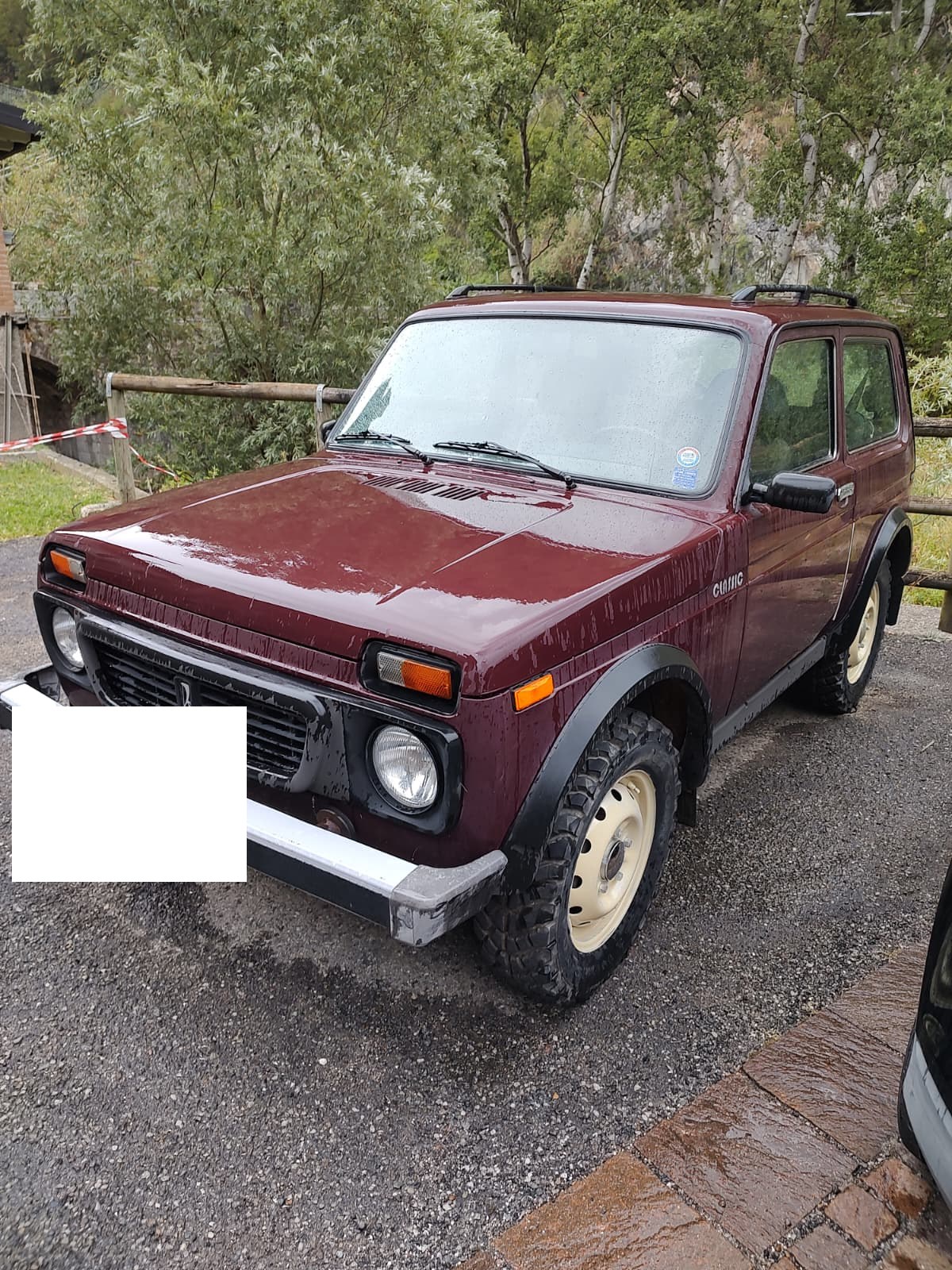 The Lada Niva parked outside, front three-quarter view, in a mountain village